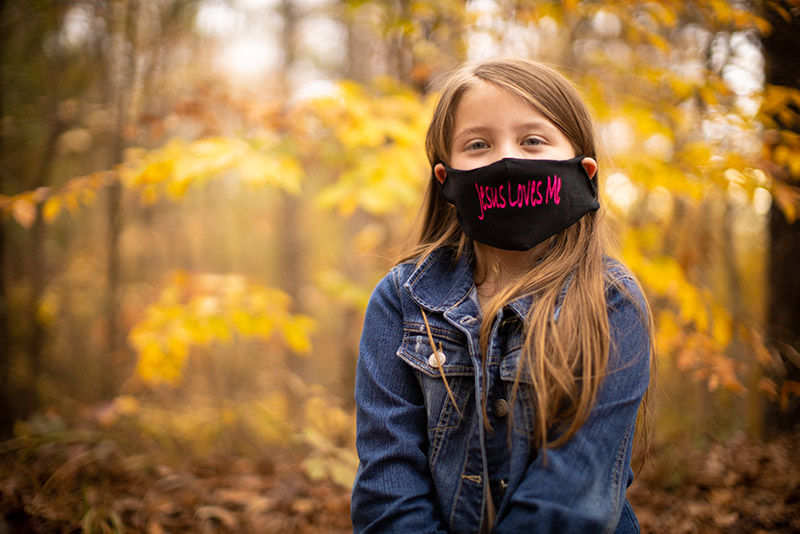 Lydia with face mask that reads 'Jesus Loves Me'.